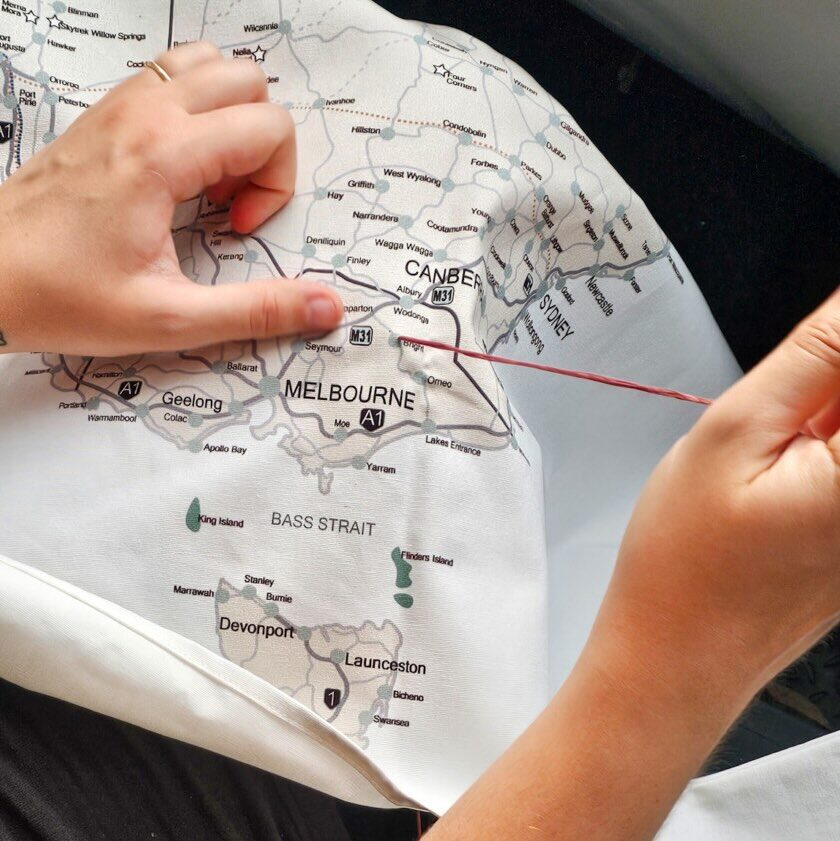 Carley's hands stitching the Map My Lap fabric over a cotton-printed Australia