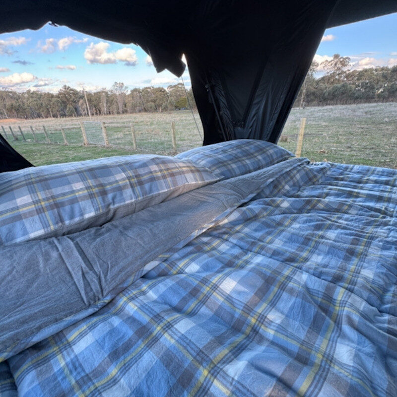Bluegum check sheet set inside a roof top tent overlooking frosted bushland